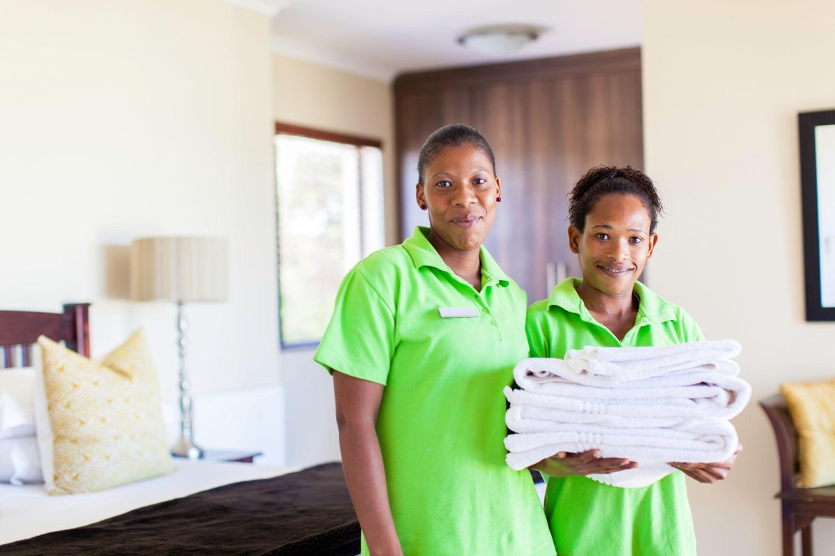African housekeeping staff holding clean towels inside a hotel room in Dubai