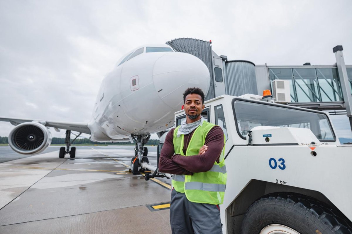 African airport ground staff worker standing beside an airplane at a European airport