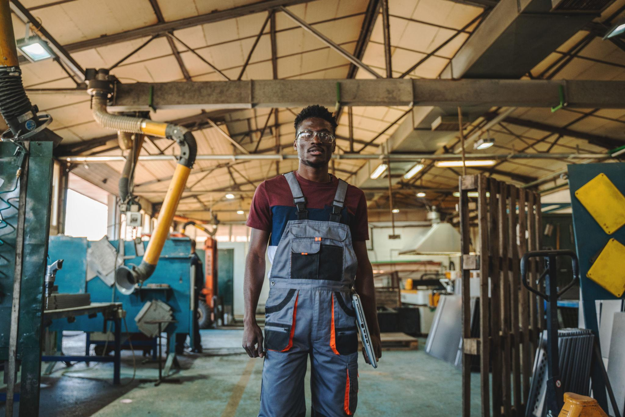 African factory worker standing inside a manufacturing facility in Poland
